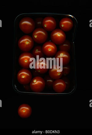 Cherry tomatoes in plastic packaging against black background Stock Photo