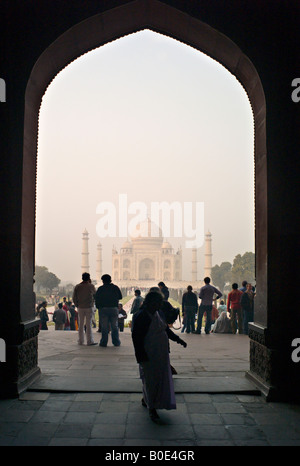 INDIA AGRA Indian tourists walk in front of the Taj Mahal at sunrise Stock Photo