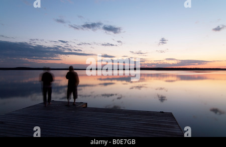 Two persons by calm lake Päijänne on quiet early summer night, Asikkala, Finland Stock Photo