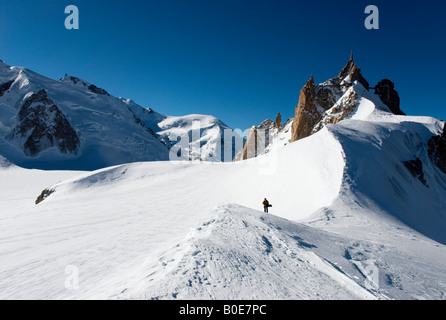 Snowboarder walking on ridge towards Grand Envers du Plan variant of Vallée Blanche, Aiguille du Midi in background Stock Photo