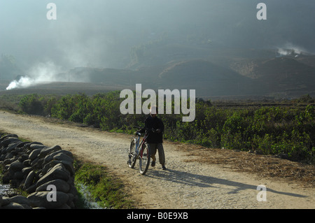 cyclist in sapa , vietnam ,behind him burning straw on a rice field, Stock Photo