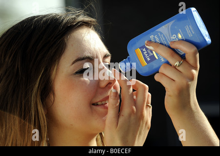 A teenage girl applies sun lotion to her face Stock Photo