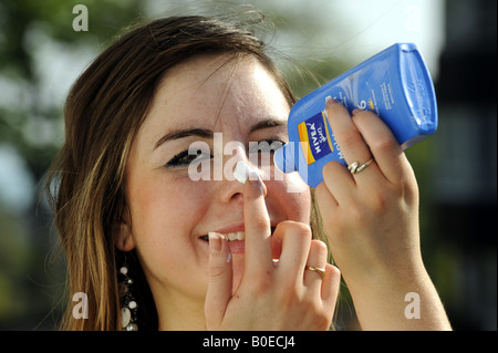 A teenage girl applies sun lotion to her face Stock Photo