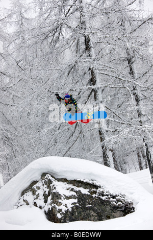 Snowboarder jumps from a rock off piste. Stock Photo