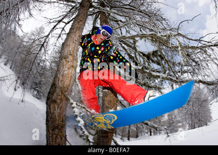 Snowboarder Jo Howard riding through a tree gap of piste in Tignes, France. Stock Photo