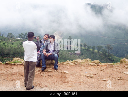 Couple posing for the camera against backdrop of tea plantations on hill slopes covered by mist Pothamadu Munnar Kerala India Stock Photo