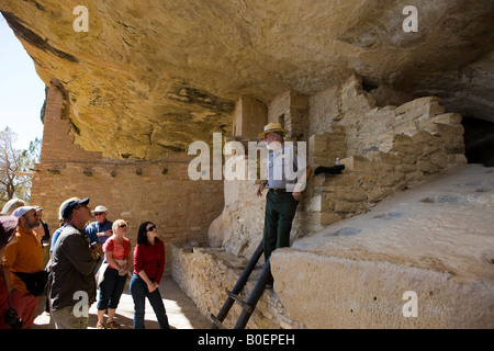 A US National Parks ranger talks to a group of visitors in the Balcony House ruins Mesa Verde National Park near Cortez Colorado Stock Photo