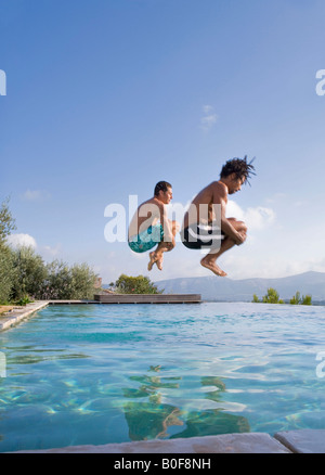 Young men jumping into a pool Stock Photo