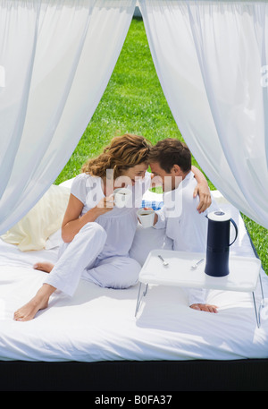 Couple having breakfast on bed in garden Stock Photo