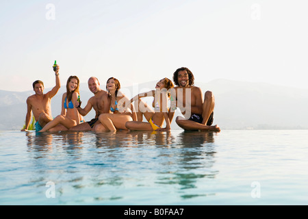 Men and women sitting by edge of pool Stock Photo
