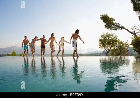 People walking by a pool, holding hands Stock Photo