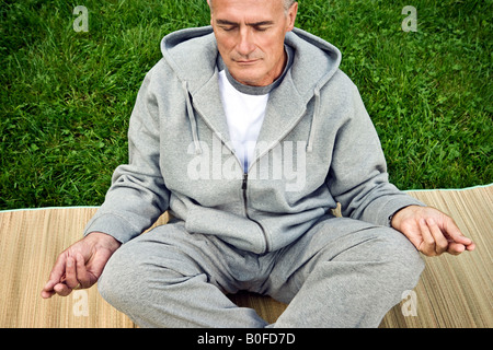 Man meditating seated on grass Stock Photo