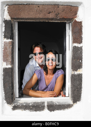 Couple looking through window, smiling Stock Photo