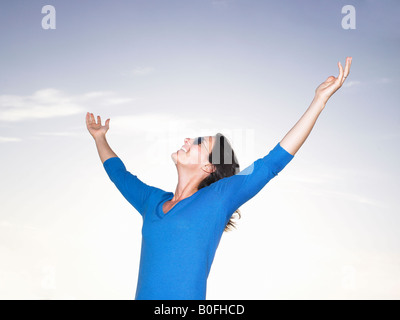 Woman stretching her arms, blue sky Stock Photo