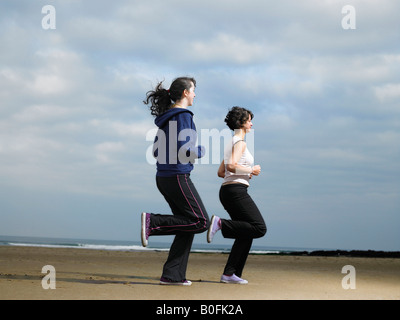 Two young females jogging on beach Stock Photo