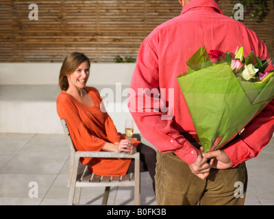 Man hiding flowers behind back Stock Photo