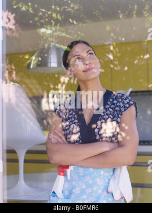 Young woman daydreaming whilst cleaning Stock Photo