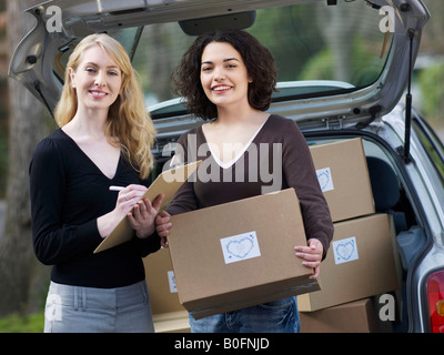 Two women checking boxes at car Stock Photo