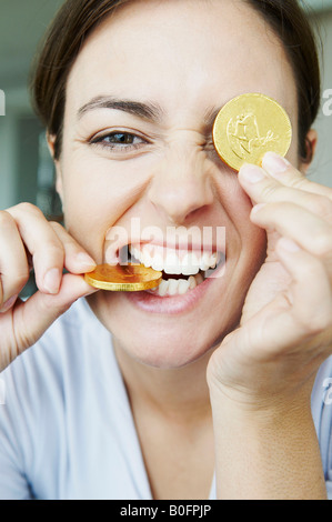 Amusing woman bites into gold coins Stock Photo