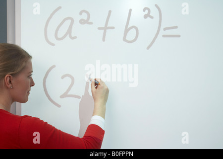 Teacher writing on whiteboard Stock Photo