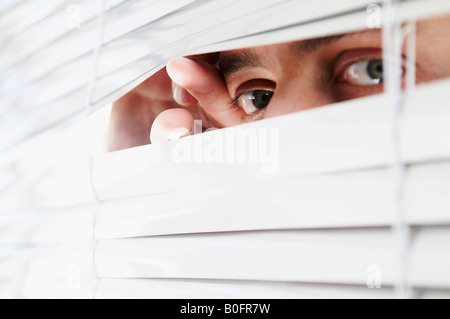 Man looking through office blinds Stock Photo