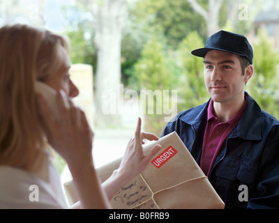 Woman on phone, courier in doorway Stock Photo