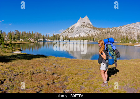 Backpacker on the shore of upper Cathedral Lake under Cathedral Peak Yosemite National Park California Stock Photo