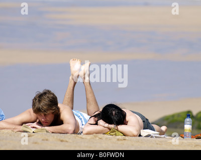 Young couple sunbathing on the beach at Newquay, Cornwall, UK Stock Photo