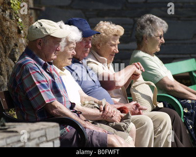 Old people sat on a bench enjoying the sunshine Stock Photo