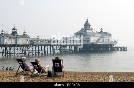Tourists relaxing in deckchairs on seafront, Eastbourne, UK Stock Photo