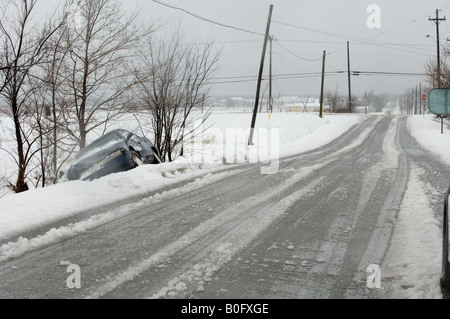 A car lies wrecked in a ditch on a country road after a heavy snowstorm. Stock Photo