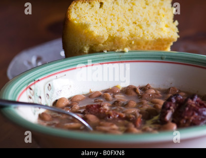 A bowl of cooked pinto beans and ham hock. A piece of cornbread rests against the bowl. Closeup. Southern cuisine, southern cooking. Oklahoma, USA. Stock Photo