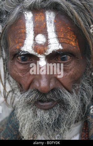 FACE PORTRAIT OF AN HINDUIST RELIGIOUS INDIAN OLD MAN WITH PAINTED FACE OUTSIDE A TEMPLE Stock Photo