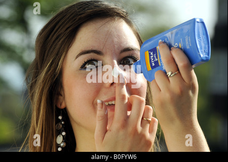 Teenage girl applies sun lotion to her face Stock Photo