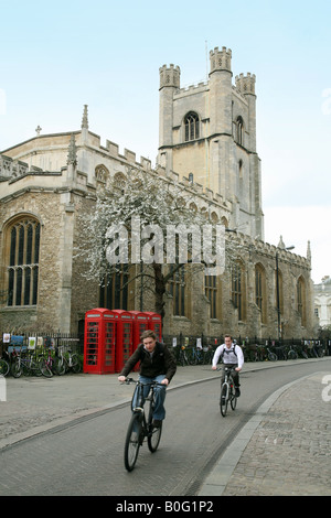 University students cycling past St Marys Church, Cambridge, England UK Stock Photo