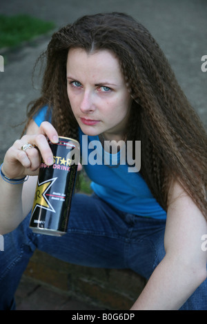 Female sitting on steps in a parking drinking a can of alcohol Stock Photo