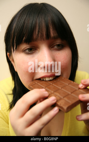 Teenage girl binge eating a large chocolate bar Stock Photo