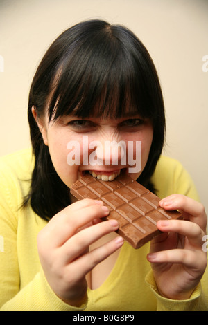 Teenage girl binge eating a large chocolate bar Stock Photo