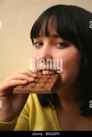 Teenage girl binge eating a large chocolate bar Stock Photo