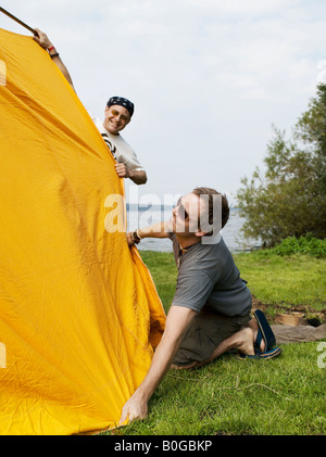 Two men setting up a tent together Stock Photo