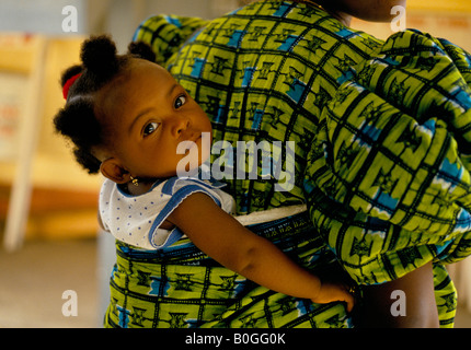 A girl on her mother's back at a health clinic, Koforidua, Ghana. Stock Photo