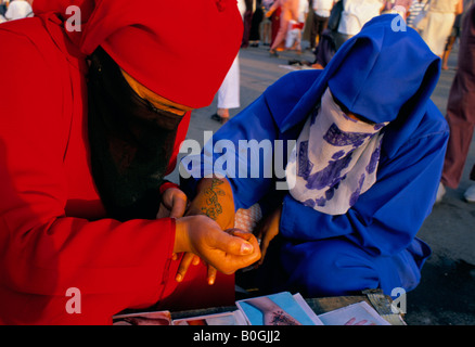 A henna artist painting a woman's hand, Marrakech, Morocco. Stock Photo