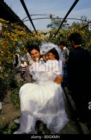 A groom carrying a bride at their wedding, Romania. Stock Photo