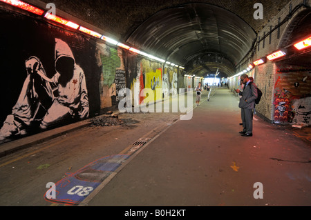 People stop to photograph Graffiti on walls of Leake Street London closed road tunnel under Waterloo train station & railway lines England UK Stock Photo