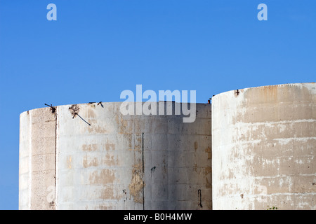 Abandoned concrete tower silos used for gypsum storage against a blue sky Stock Photo