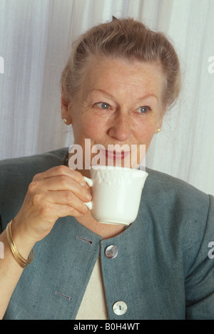 elderly woman drinking tea and looking pleased Stock Photo