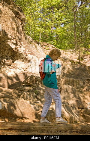 Caucasian Woman (50-55) Balances while Walking on Log at Petit Jean State Park Entrance Sign Arkansas USA Stock Photo