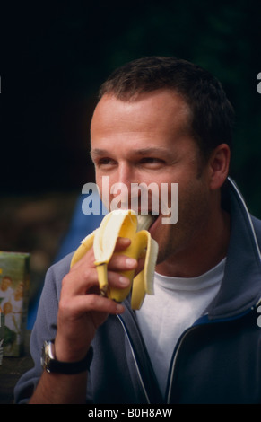 Forty-year-old man eating a banana Stock Photo