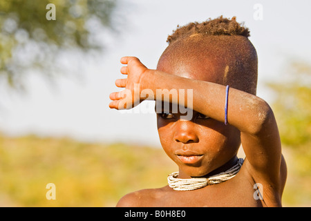 Himba boy shielding his eyes from the sun, Kaokoveld, Namibia, Africa Stock Photo