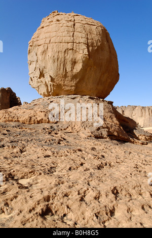 Eroded rock formation, round boulder balanced on a rock base in Tin Akachaker, Tassili du Hoggar, Wilaya Tamanrasset, Algeria,  Stock Photo